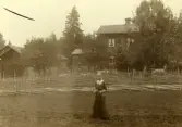 Sommaren 1913.  Fröken Anna (el.Karin) Wikman (i Hudiksvall) står framför sin mors släkts hem i Växbo, Bollnäs socken.