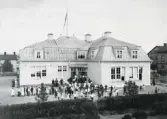 Bollnäs. Omkr. 1910. Södra skolan, senare kallad Bro-skolan, byggdes 1901-02 och revs 1973.
Bilden är fr. något mer högtidligt tillfälle än en vanlig skoldag. Kan troligen vara en skolavslutning.
Eleverna står i ring ute på skolgården.

(Läsåret 1967-68 var det sista m. skolverksamhet. Fritidsnämnden hade ungdomsgård i fastigheten 1969-1972. Efter påpekanden från brandmyndigheterna bedömde de kommunansvariga att det skulle bli för kostsamt att rusta upp fastigheten, varför den revs. )