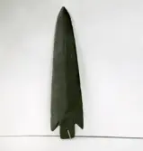 Spets i mörkröd skiffer, funnen 1878 i Sörbo by. Bollnäs. Funnen i sjöbottnen (ristat i spetsen) vid dytäkt. Många år efter hittades en liknande (?) spets, trol. mindre, upp i backen.