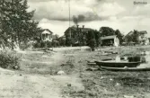 Gårdar intill en strandkant i Bollnäsområdet. Några båtar ligger i vattnet.