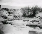 Fruset vattendrag med fall. Till vänster ses en person i kanten. Okänd fotograf.