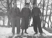 Snöbild. Tre män står utomhus i snön med träd och ett vattendrag i bakgrunden. Se även bildnr GB2_4329 från samma plats.