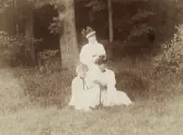 Tre sommarklädda kvinnor i en grässlänt. Ingjerd Sellergren (g. Sandström), fru Elsa (Eja) Laudien (f. Eksandh) och i mitten fröken
Sally Eksandh, 
Evedal (?), Ronneby brunn (?).