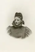 En ung kvinna i höghalsad vinterjacka med sammetshatt och flor.
Bröstbild, halvprofil. Ateljéfoto.
Elsa Eksandh (senare g. Laudien).