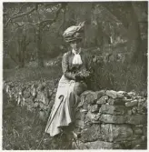 En kvinna i blus, kjol och hatt sitter på en stenmur i en park. Bad Kissingen (?).
Elsa Eksandh (g. Laudien).