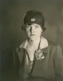 En ung kvinna i klänning. kappa och hatt med brosch, m.m.
Bröstbild, halvprofil. Ateljéfoto. (Passfoto?).

Margareta Bergstedt (senare g. Lidén), Växjö.