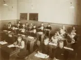 En skolklass med flickor och pojkar i ett klassrum.
Klass 1, Flickskolan (?), Växjö, 1907. 
I bakersta raden, 6:e fr. v. syns Margareta Bergstedt.