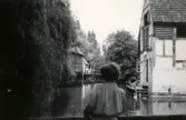 Fotografi från 1949 som visar en vy från friluftsmuseet Den Gamle By i Danmark. Vi ser Inga-Lill Börjesson som har vänt ryggen åt kameran vid fotograferingsögonblicket.