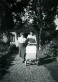 Lennart Berndtsson, i barnvagnen, är ute på promenad med sin mor Inga Maj Berndtsson samt sin gudmor. Solhemsgatan 35 på Solängen i Mölndal, cirka 1954.