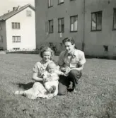 Porträtt av pojken Lennart Berndtsson med sin faster Ulla Kihlqvist och farbror Gösta Kihlqvist.. De sitter i gräset mellan husen i ett bostadsområde. Prytzgatan i Broslätt, Mölndal, sommaren 1954.
