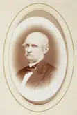 En medelålders man med mustascher, klädd i mörk kostym med stärkkrage och fluga.
Bröstbild, halvprofil. Ateljéfoto.
Överste Samuel Otto Gustaf af Klint (1815-1878), Växjö, gift med friherrinnan Elise Rappe (1827-1918).