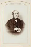 En man i mörk kostym med väst sitter och tar en pris snus ur en snusdosa.
Knäbild, halvprofil. Ateljéfoto.
Brukspatron Carl Aschan (1812-1886), Karlsjö bruk m.m., senare bosatt i Växjö. Gift med Ottiliana (Ottil) Wrede af Elimä (1816-1901).