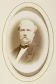 En skäggig medelålders man i mörk kostym med stärkkrage och fluga.
Bröstbild, halvprofil. Ateljéfoto.
Kammarherren m.m. Ferdinand Gyllensvärd (1811-1889), Åby, Tjureda. Gift med Hélène Charpentier (1819-1915).