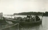 En grupp människor som sitter i en båt och kanske på väg ut på roligheter, tidigt 1900-tal.