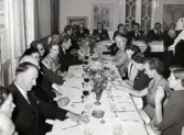 50-årsjubileum den 3 juli 1954 för Kustsanatoriet Apelviken. Middagsgäster vid långbord i Societetsrestaurangen. Några studerar menyn, andra tar en cigarett. (Se bildnr KSA137-KSA159.)