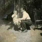 Farfar Bertil Berndtsson gungar pojken Lennart Berndtsson, cirka 1955. Gungan hänger från ett träd. Fotografi eventuellt taget i Lödöse.