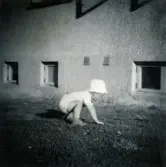 Pojken Lennart Berndtsson tar sig fram på alla fyra. Ett bostadshus i bakgrunden. Prytzgatan i Broslätt, Mölndal, cirka 1955.