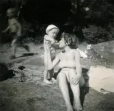 Pojken Lennart Berndtsson förser sin mamma Inga Maj Berndtsson med något att dricka ur en flaska vid badplatsen 