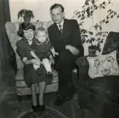 Porträtt av pojken Lennart Berndtsson tillsammans med hans föräldrar Inga Maj och Leif Berndtsson. De sitter i ett vardagsrum. Tolsegårdsgatan 4 i Bosgården, Mölndal, hösten 1955.