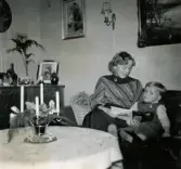 Jul på Prytzgatan 38 i Broslätt, Mölndal, cirka 1957. Pojken Lennart Berndtsson och hans faster Ulla Kihlqvist sitter i soffan i vardagsrummet.