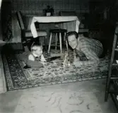 Jul på Prytzgatan 38 i Broslätt, Mölndal, cirka 1957. Pojken Lennart Berndtsson leker på golvet i vardagsrummet tillsammans med sin farbror Gösta Kihlqvist.