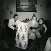 Julafton på Prytzgatan i Broslätt, Mölndal, år 1958. Pojken Lennart Berndtsson sitter tillsammans med sin far Leif Berndtsson och tomten i vardagsrummet.