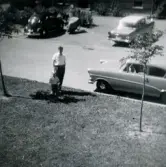 Pojken Lennart Berndtsson och hans farbror Gösta Kihlqvist står intill en parkerad bil vid sidan av Tolsegårdsgatan i Bosgården, Mölndal, cirka 1958.