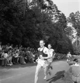 Idrottstävlingar på Värendsvallen, 1944.
Löpning för herrar. Gunder Hägg i täten. Till höger sitter en man
på huk och fotograferar.
