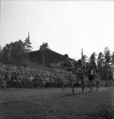 Idrottstävlingar på Värendsvallen, 1944.
Löpning för herrar. Gunder Hägg i täten. I bakgrunden syns hedersläktaren.