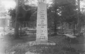 Fotografi av en minnesvård rest över stupade i 1808–1809 års Finska kriget. Monumentet utgörs av en hög, rektangulär stenobelisk placerad på sockel i en trädbevuxen miljö, sannolikt kyrkogård eller minnesplats. På stenen finns inskriptionen: ”HÄR DELA SAMMA BÄDD FIENDE OCH VÄN FRÅN RYSKA KRIGET 1809 † 1883 RESTES VÅRDEN.” Runt minnesmärket syns trästaket, bänkar samt en timrad byggnad i bakgrunden. Vården uppfördes 1883 till minne av soldater från kriget.