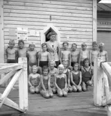 Simningen, 16/8 1942. 
Foto av en barngrupp med ledare, framför badhuset på Evedal.