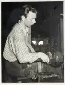 Verksamhet i hyttan på Strömbergshyttan.
En man formar ett föremål med skopa.