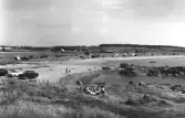 Ugglarps havsbad. Strandvy med badande och solande människor. Bilar parkerade på stranden till vänster. Förlag: Konsum, Ugglarp 1962. 
Numreringen är AB Flygtrafiks med prefixet FF. Samtliga versioner, såsom neg, fotokopior, vykort etc, i AB Flygtrafiks bildsamling har alltid samma reg.nummer.