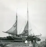 En galeas som ligger förtöjd i en hamn där en kvinna och två barn syns i förgrunden. Torekov, Skåne 1922.