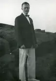 Tandläkare Gunnar Högberg uppklädd i kavaj och fluga stående på en klippa i Torekov, Skåne 1922.
