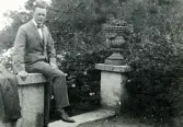 Tandläkare Gunnar Högberg sittande på en mur bredvid en klassisk urna i Båstad, Skåne 1922.