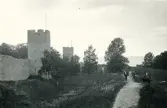 Ett sällskap som promenerar längs en stig och längs med en del av ringmuren i Visby, Gotland 1927.