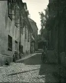 Bild av en gränd i Visby, Gotland 1927, med stenhus längs en kullerstensbelagd gata.