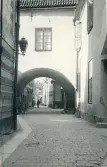 Bilden visar en smal gränd med kullerstensbeläggning och en karaktäristisk överbyggnad/valv i Visby, Gotland 1927.