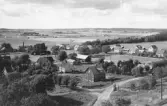 Årstads kyrkby. Bilden är tagen från kyrktornet med vy över bybebyggelsens villor och mindre gårdar. I bakgrunden breder odlingslandskapet ut sig. Förlag: Th. Persson, Årstad.