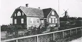 Folkskolan i Heberg. En väderkvarn syns till höger om skolan. Bild 2 är ett sepiatonat vykort.