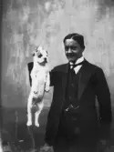 Man håller hundvalp i nackskinnet, 1912