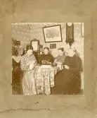 Fyra kvinnor som sitter och handarbetar i heminteriör.