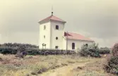 Träslövsläge kyrka med omgivande häck och natur. Den 6 december 1926 ringde fiskelägets kyrkklocka för första gången, och på juldagen samma år hölls den första gudstjänsten. Kyrkan är byggd av Bröderna A & C W Gustafsson, Borås, efter ritningar av arkitekt Sigfrid Ericson, Göteborg. Dessförinnan hade man fått ta sig 8 km till församlingskyrkan i Träslöv. Redan på 1910-talet hade önskemål framkommit om att få bygga en kyrka i Träslövsläge och en kollekt som togs upp i Träslövs kyrka juldagen 1913 blev grundplåten till detta. Man fortsatte att samla in medel och slutligen anlitades på 1920-talet arkitekt Sigfrid Ericsson. Han var rektor för Slöjdföreningens skola i Göteborg och hade bl a ritat Masthuggskyrkan i Göteborg. Ericsson ritade även Brämaregårdens kyrka invigd 1925, som är mycket lik Träslövsläges kyrka; båda är av trä och i nyklassicistisk stil med fasadpilastrar, stickbådade fönster och klockportar samt runda fönster på de kraftiga tornen med flackt pyramidtak.