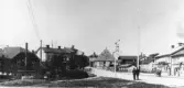 Vy över Oxtorgsgatan och Kvarngatan i stadsdelen Väster, Söderhamn. Till vänster Garnbutiken i f.d. gevärsfaktoriets borrhus, numera Söderhamns stadsmuseum. Foto från omkring 1900 - 1910.