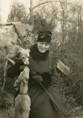 Porträtt av en kvinna med två hundar som sitter ute i naturen.