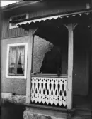 Kvinna står ute på förstukvist, Uppland