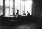 En man och två kvinnor sitter vid kaffebord, Uppsala
