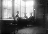 En man och två kvinnor sitter vid kaffebord, Uppsala
