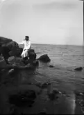 Enok Hällbom klädd i badrock sitter på klippan vid vattnet och röker pipa, Sverige
